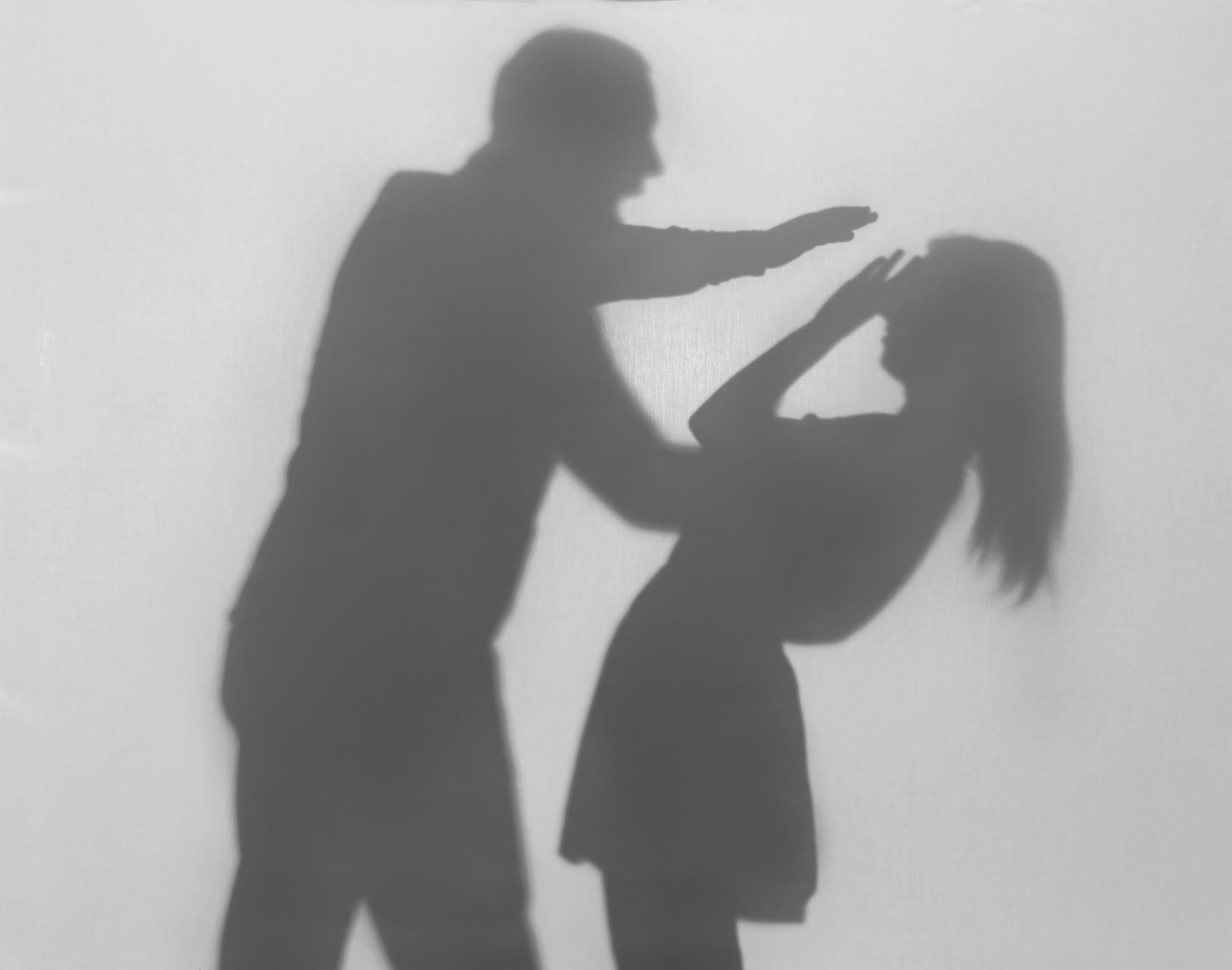 Silhouette of man hurting his wife on white background. Domestic violence concept