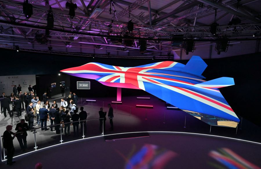 Caption: Delegates look at the Global Combat Air Programme (GCAP) 6th generation fighter jet concept design, bathed in the colours of the United Kingdom's national flag, on the opening day of the Farnborough International Airshow 2024, south west of London, on July 22, 2024. AFP/Justin Tallis