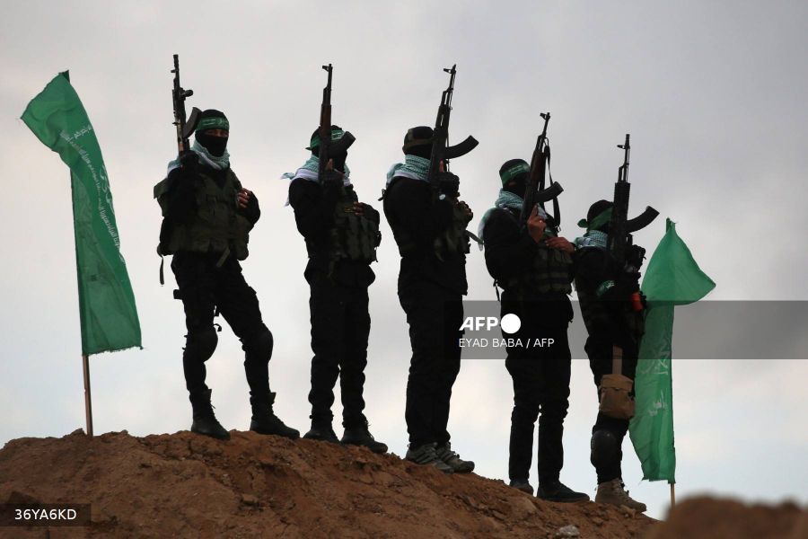 Caption: Palestinian Hamas militants gather at the site of the handing over of the bodies of four Israeli hostages in Khan Yunis in southern Gaza on February 20, 2025. AFP/Eyad Baba