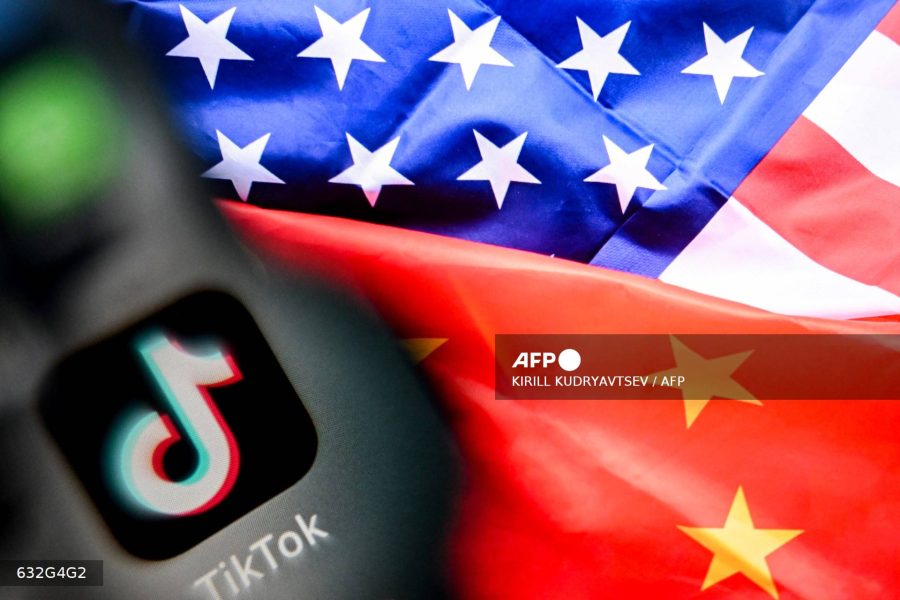 Caption: A photo taken on April 10, 2025, shows the Chinese social networking service TikTok's logo on a smartphone screen, left, and US and China flags combo illustration on a laptop screen in Frankfurt am Main, western Germany