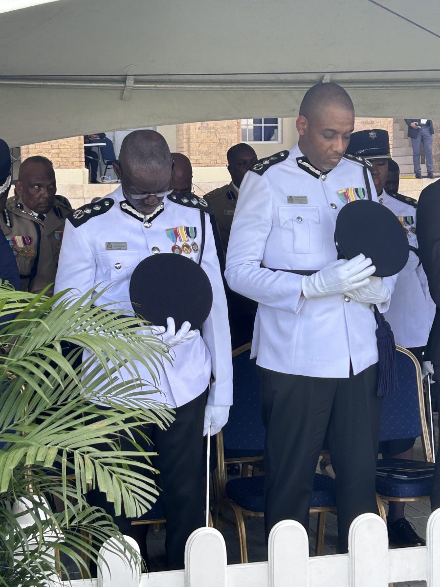 Former acting Commissioner of Police Junior Benjamin, left and newly appointed Commissioner of Police Allister Guevarro bow their heads in silence during the opening prayer of Guevarro's appointment ceremony on Tuesday at the Police Barracks, St James. AZP News/Alicia Chamely