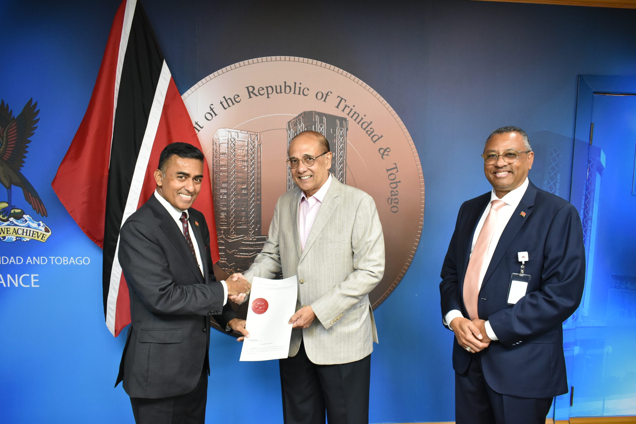 Caption: Minister of Finance Davendranath Tancoo presents Larry Howai as Central Bank Governor as Minister in the Ministry of Finance Kennedy Swaratsingh looks on