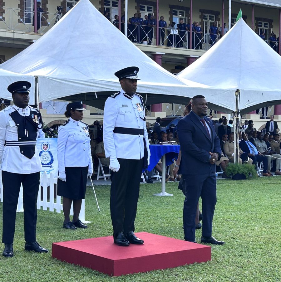 Commissioner of Police Allister Guevarro, on podium, and Minister of Homeland Security Roger Alexander, right, stand at attention at Guevarro's ceremony of appointment on Tuesday at the Police Barracks, St James. AZP News/Alicia Chamely