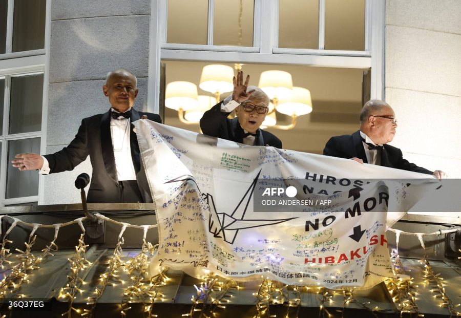 The representatives of the 2024 Nobel Peace Prize winner Japan's atomic bomb survivors' group Nihon Hidankyo (L-R) Toshiyuki Mimaki, Terumi Tanaka and Shigemitsu Tanaka hold a banner while standing on the balcony of the Grand Hotel in Oslo, Norway on December 10, 2024. - (Photo by Odd ANDERSEN / AFP)
