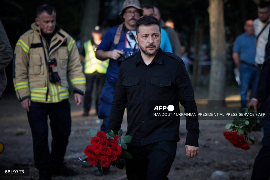 Caption: This handout photograph taken and released by Ukrainian Presidential Press-service late on August 1, 2025 shows the President Volodymyr Zelensky arriving to lay flowers in front of a residential building in Kyiv partially destroyed following a Russian missile strike morning on July 31, 2025.