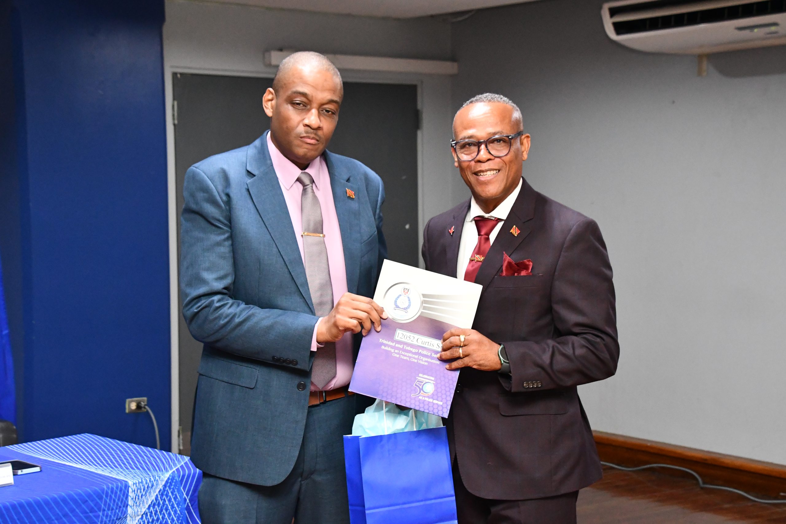 Caption: Commissioner of Police Allister Guevarro, left,  hands newly promoted Senior Superintendent of Police Curtis Simmons his letter of promotion. Photo: TTPS