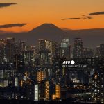 A general view shows Japan's highest mountain, Mt. Fuji (3,776m or 12,388 feet) and skyscrapers in central Tokyo at sunset on November 17, 2025.