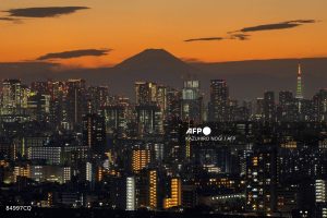 A general view shows Japan's highest mountain, Mt. Fuji (3,776m or 12,388 feet) and skyscrapers in central Tokyo at sunset on November 17, 2025.